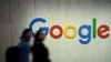FILE PHOTO: People walk next to a Google logo during a trade fair in Hannover Messe
